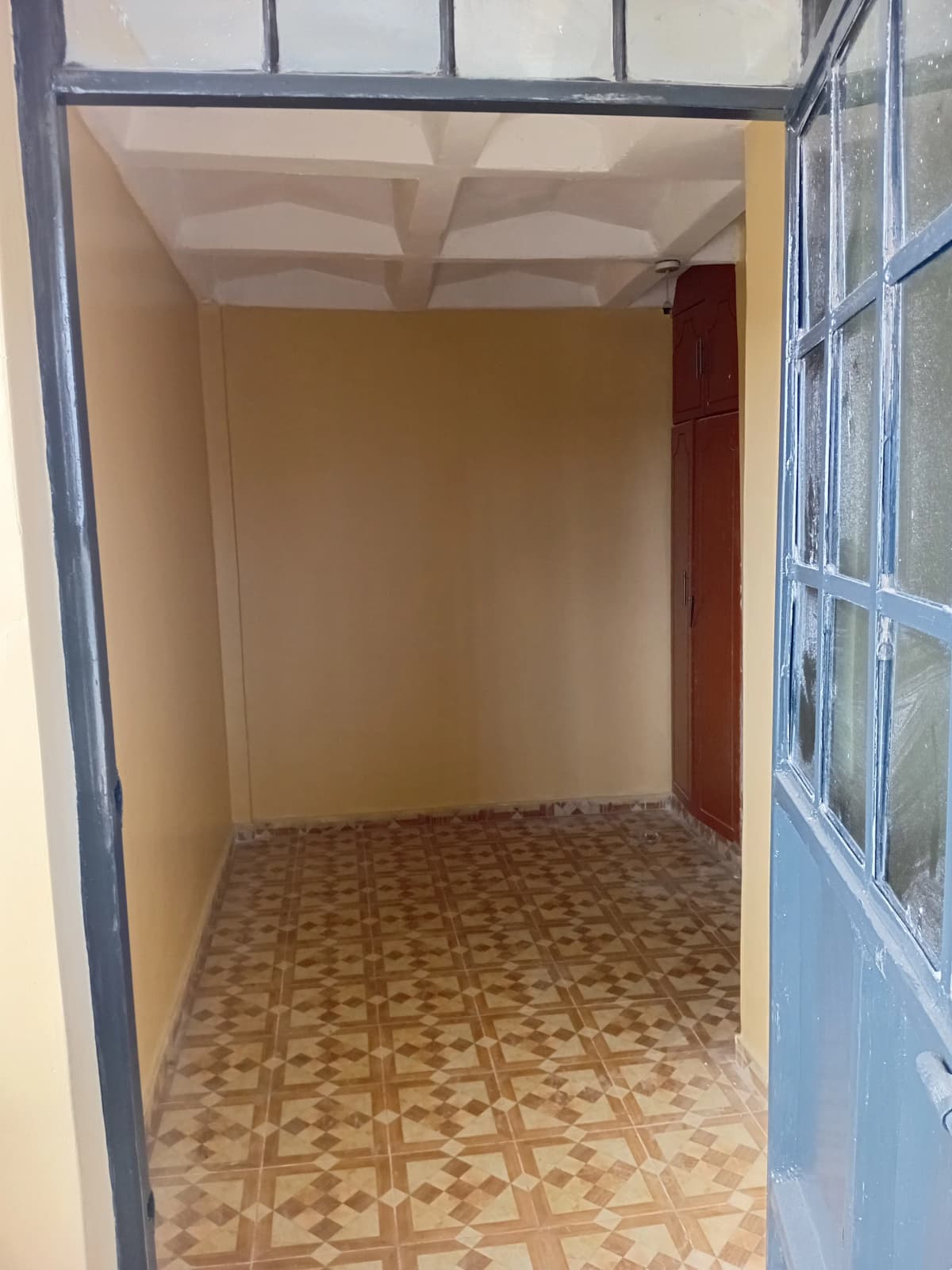 Empty room with geometric floor tiles and coffered ceiling