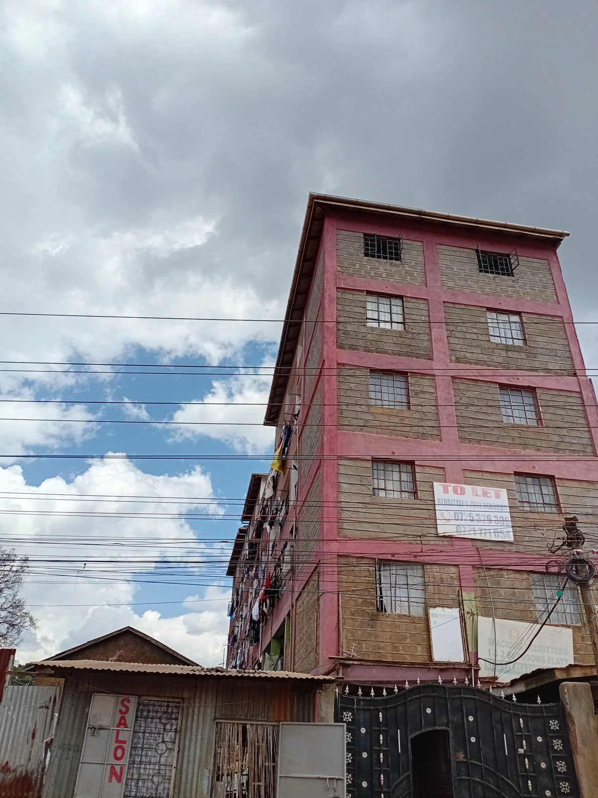 Pink multi-story residential building with grid windows and gate