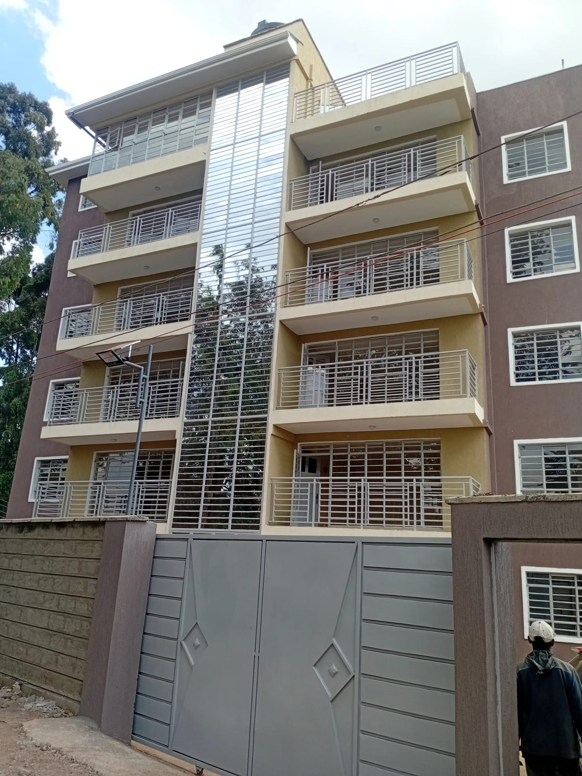 Modern multi-story residential building with balconies and metal gate