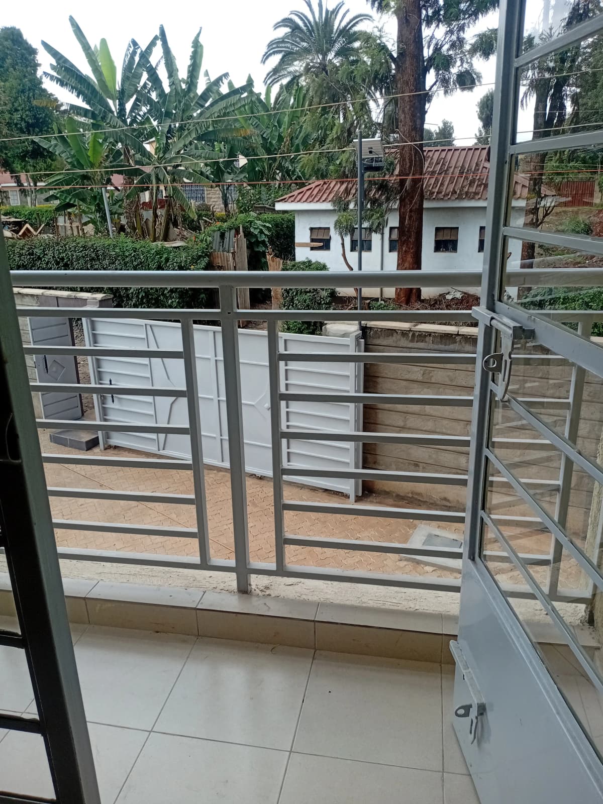 Balcony with metal railing overlooking garden and compound