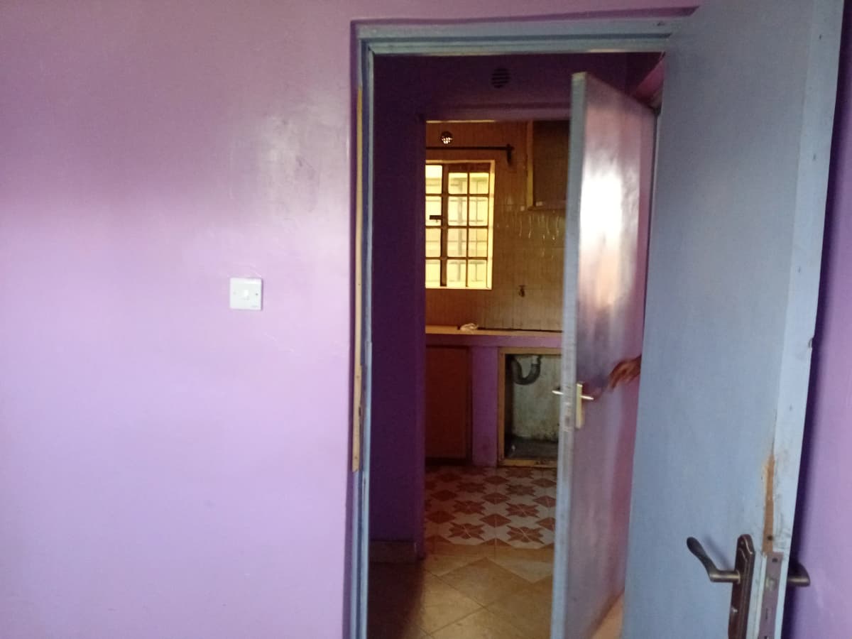 Narrow hallway with pink walls and checkered floor tiles