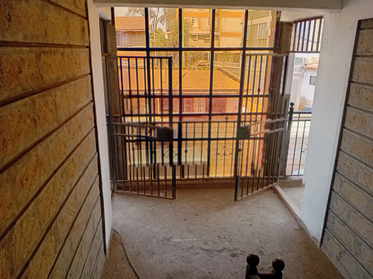Balcony with metal safety gate overlooking compound courtyard