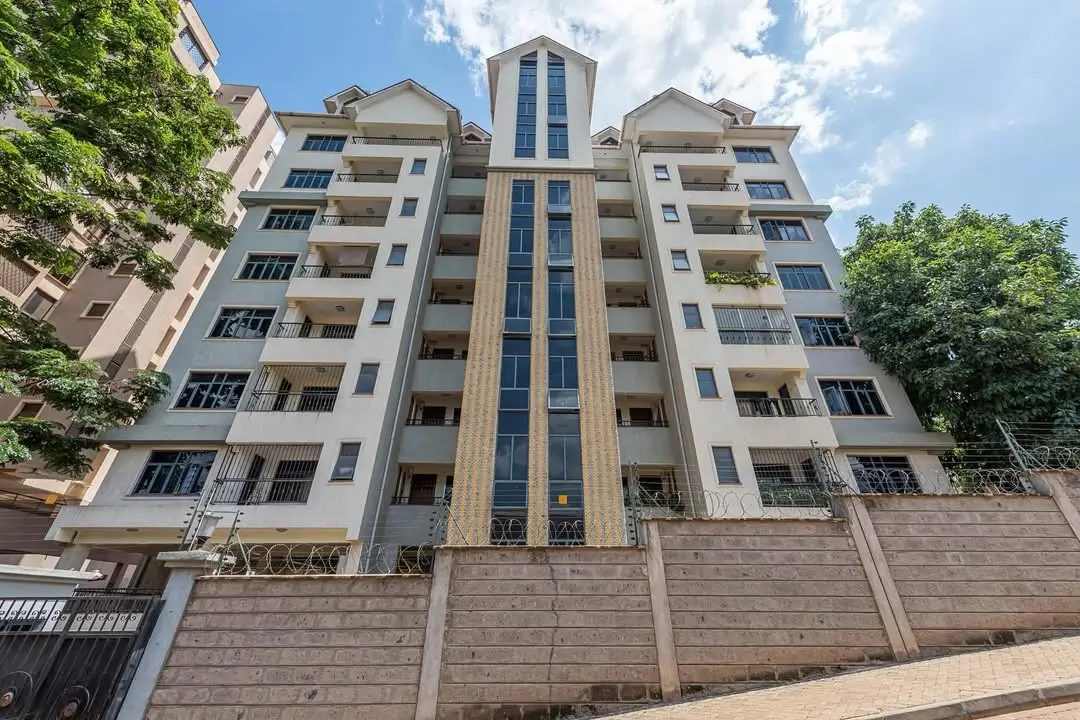 Modern multi-story residential building facade with manicured compound grounds
