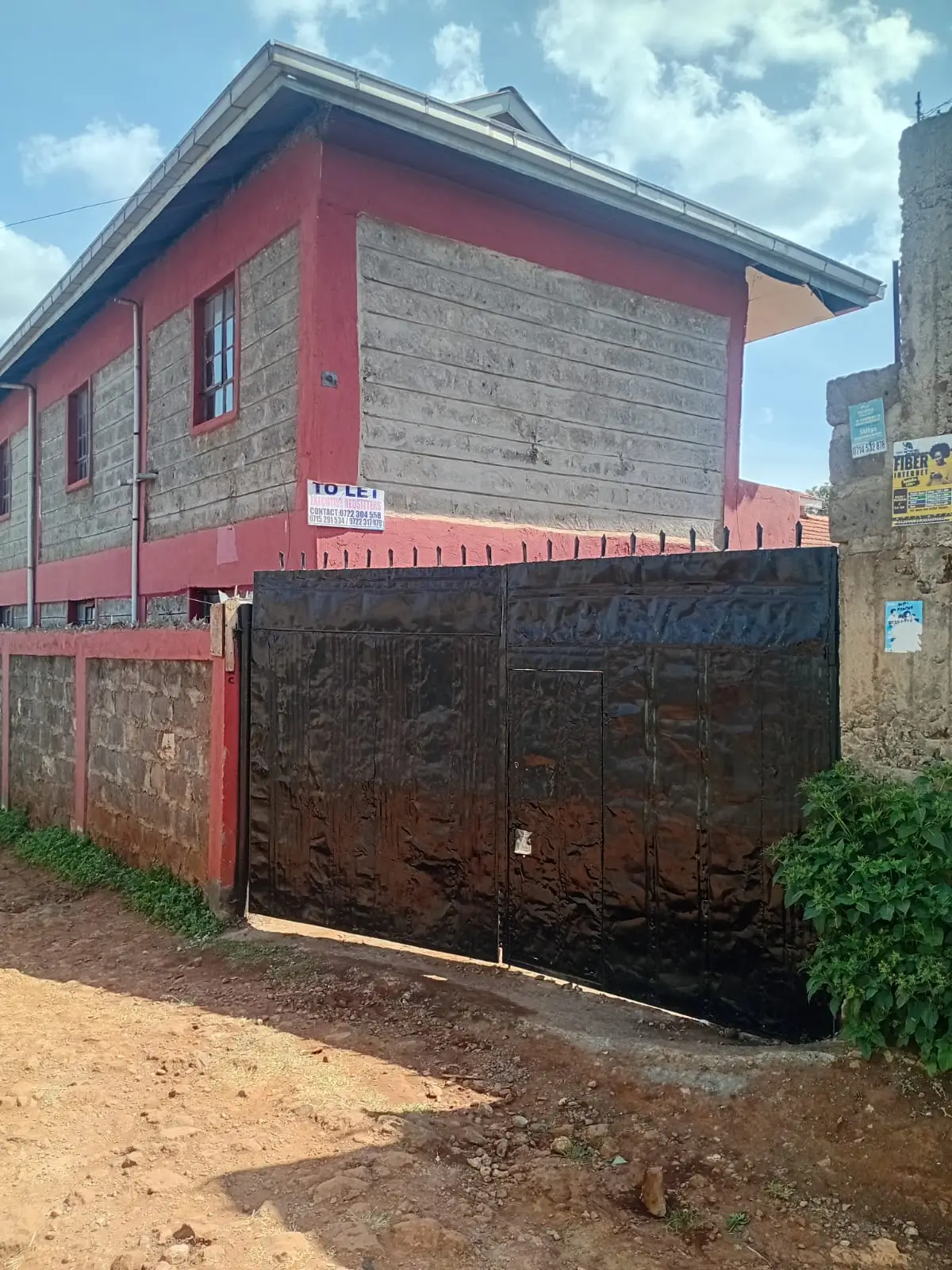 Red and stone residential building with metal gate entrance