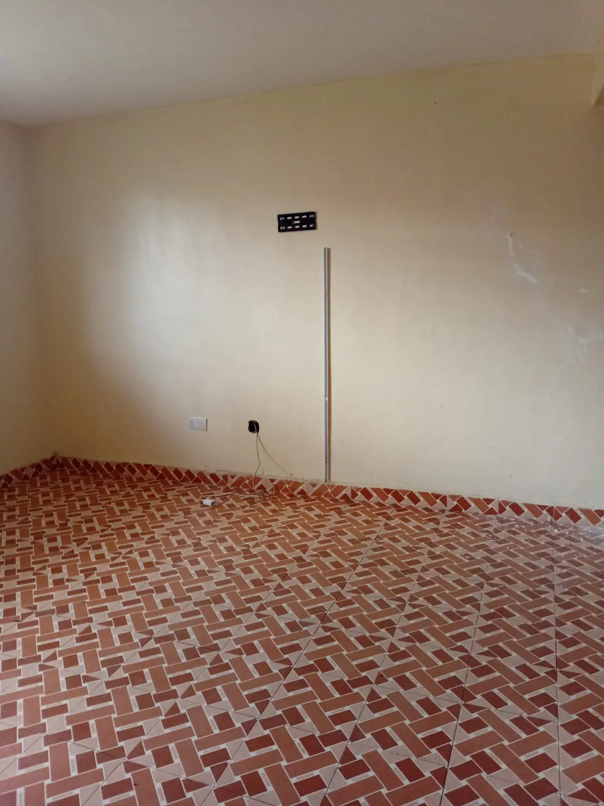 Empty bedroom with herringbone tile floor, bare walls