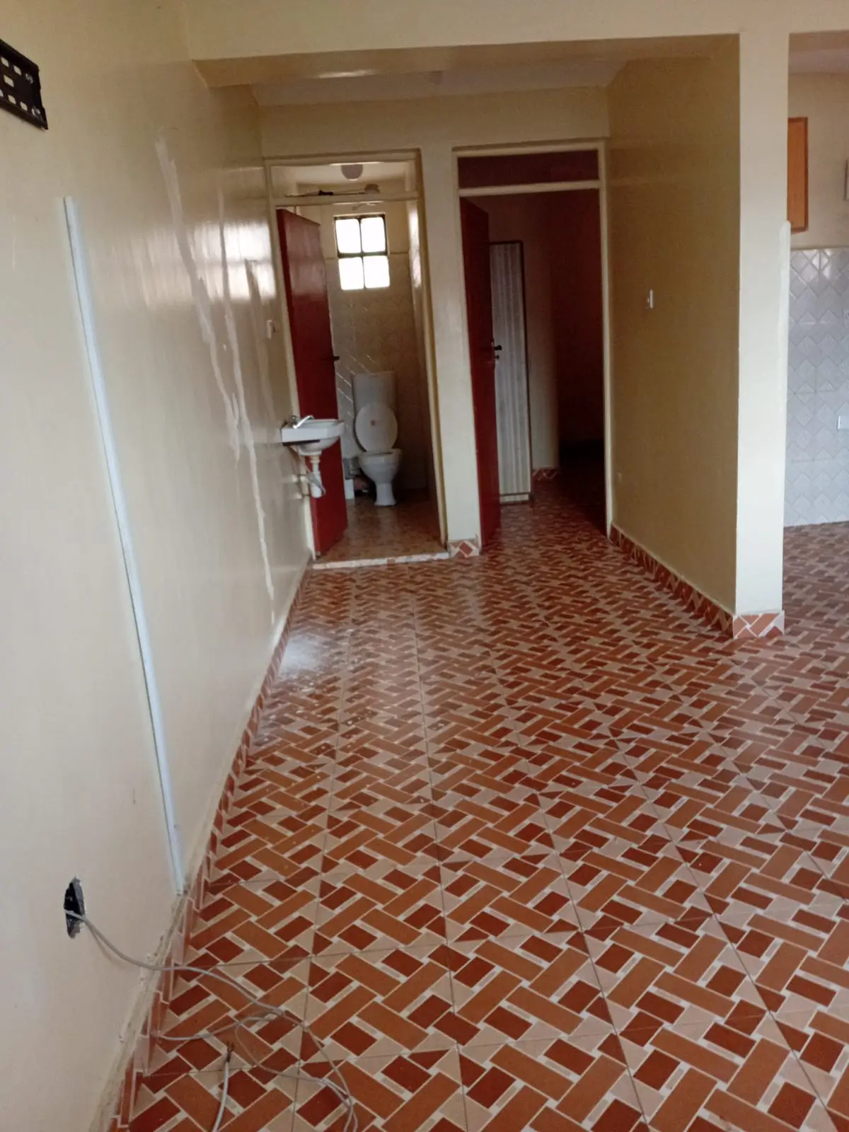 Hallway with herringbone brick flooring, bathroom visible ahead