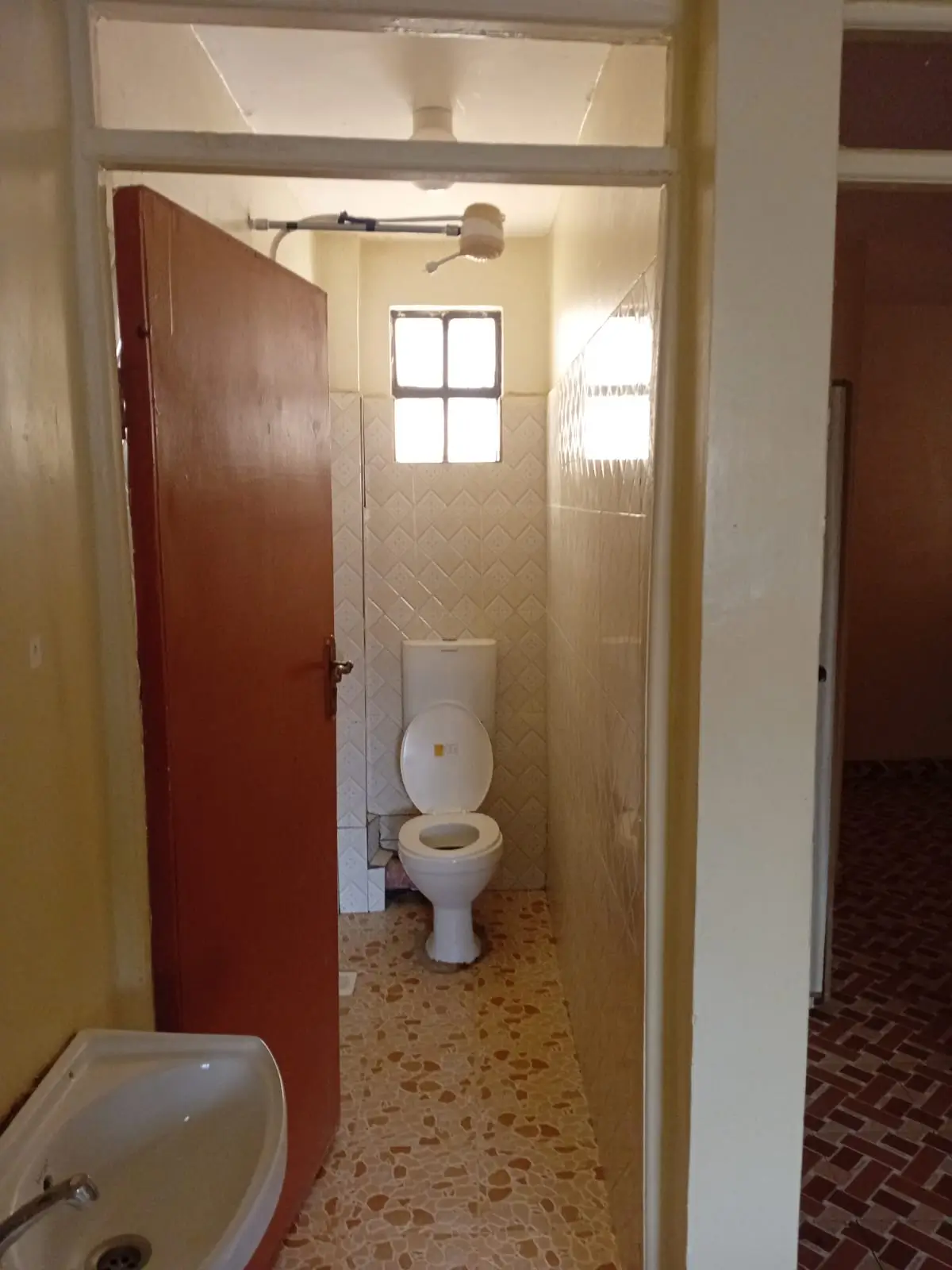 Narrow bathroom with toilet, sink, and tiled walls.