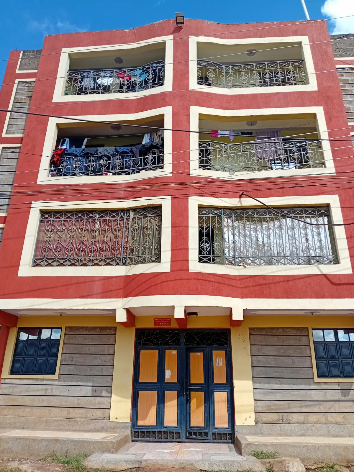 Red and yellow multi-story residential building facade with balconies
