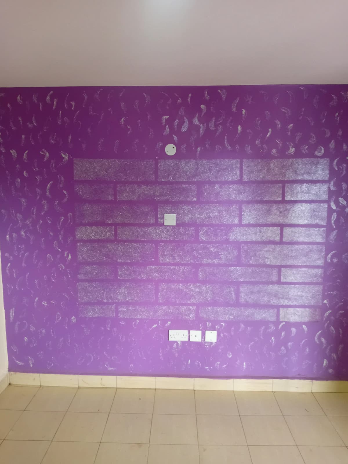 Empty room with purple accent wall and exposed brick pattern
