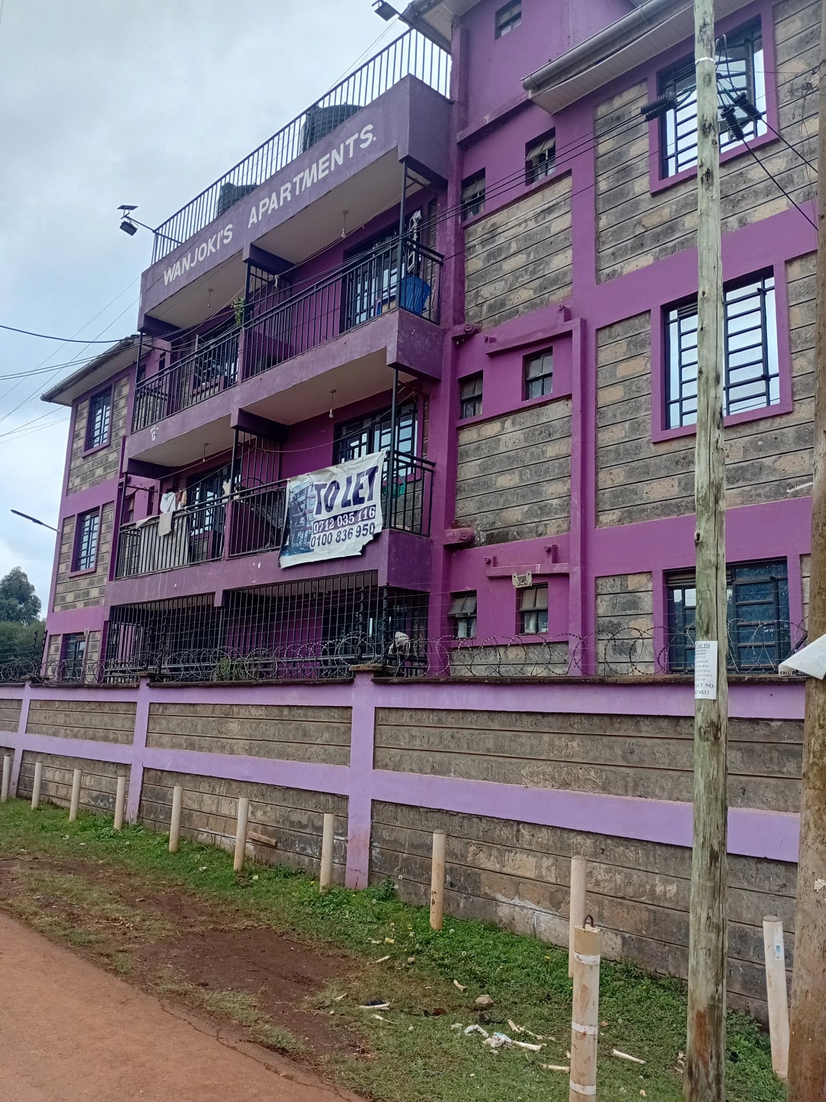 Purple apartment building facade with balconies and white fence