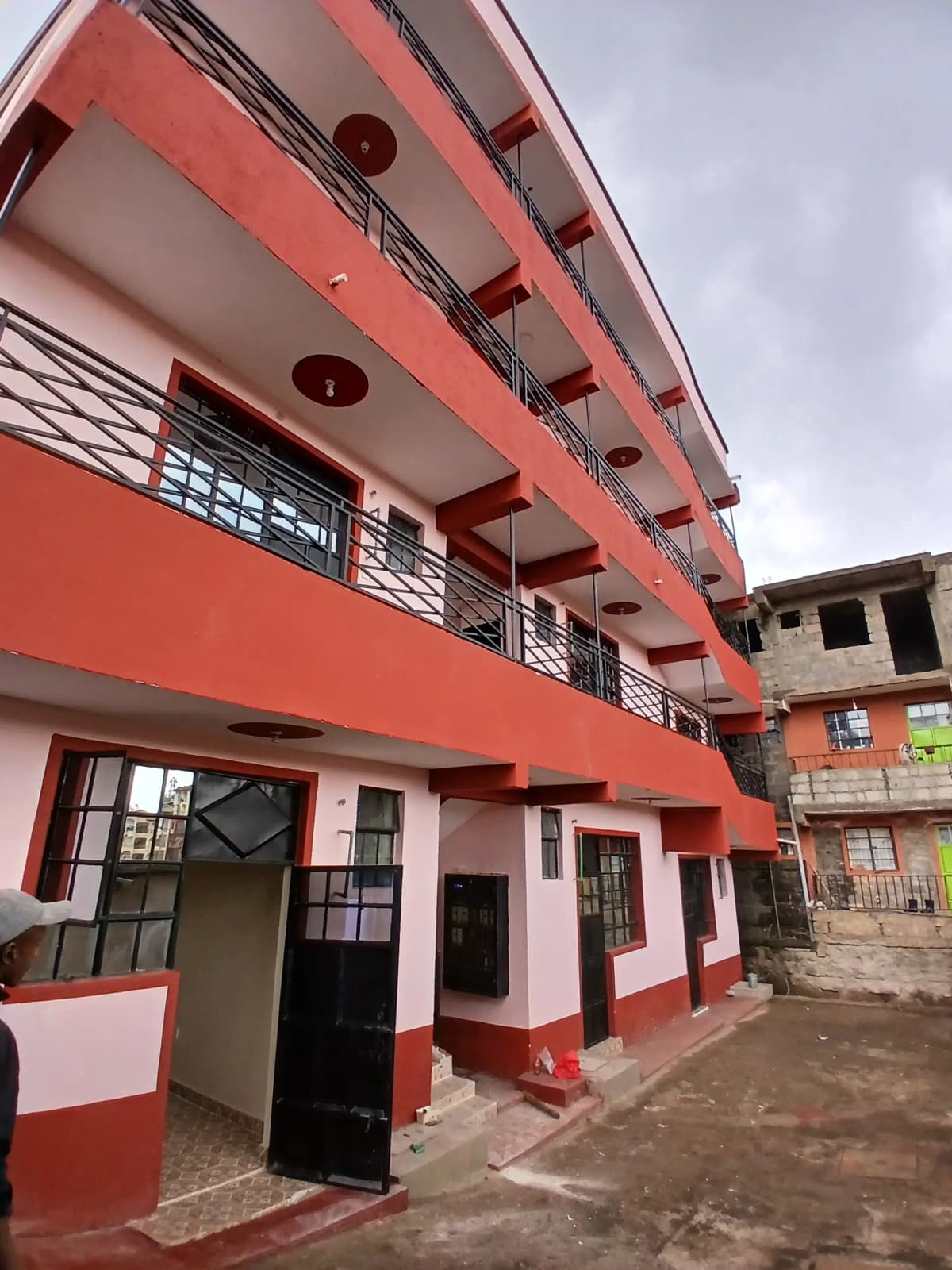 Red residential building facade with multiple unit balconies.