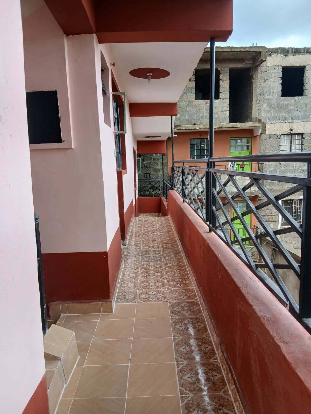 Red-trimmed balcony or terrace with tiled walls overlooking construction.