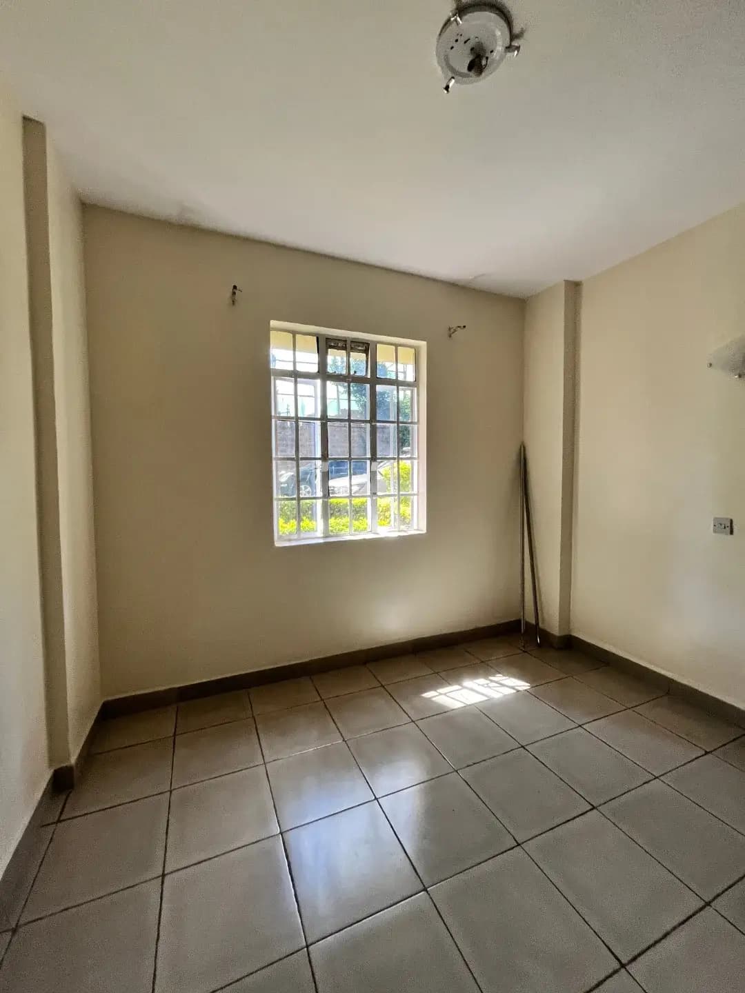 Empty bedroom with tiled floors and natural light window