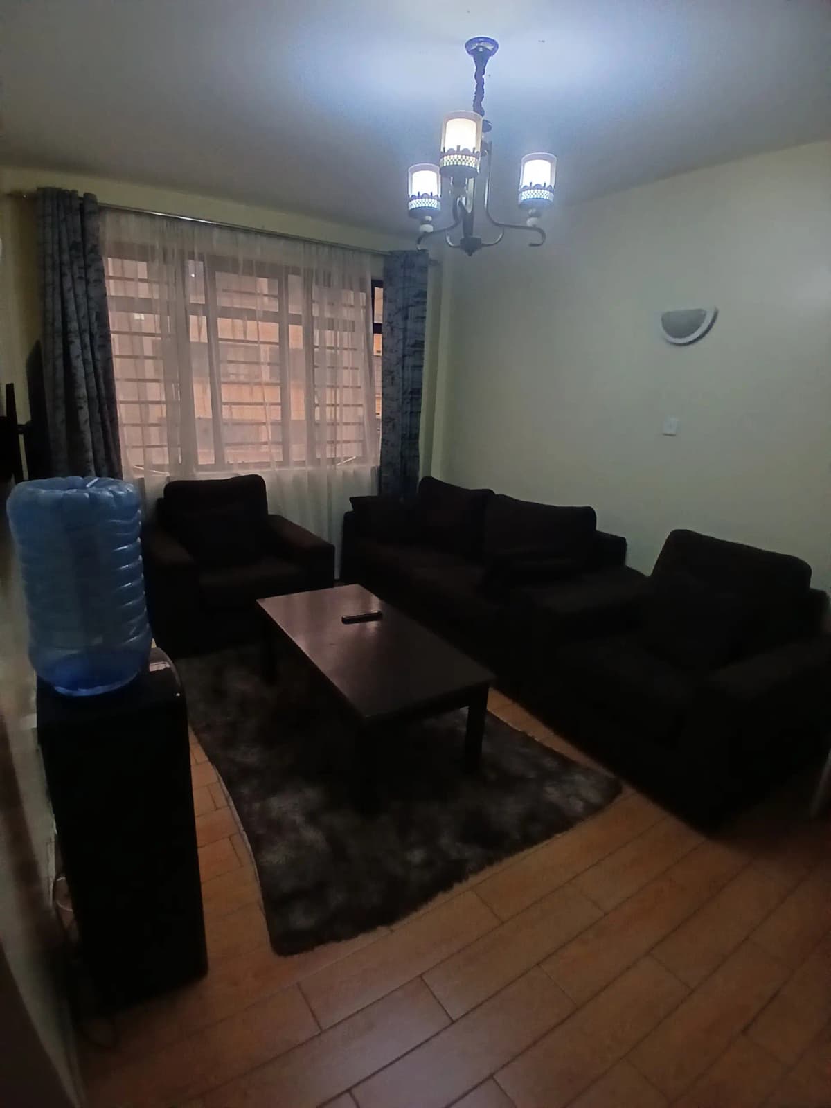 Dark lounge with black sofas, chandelier, and brick view