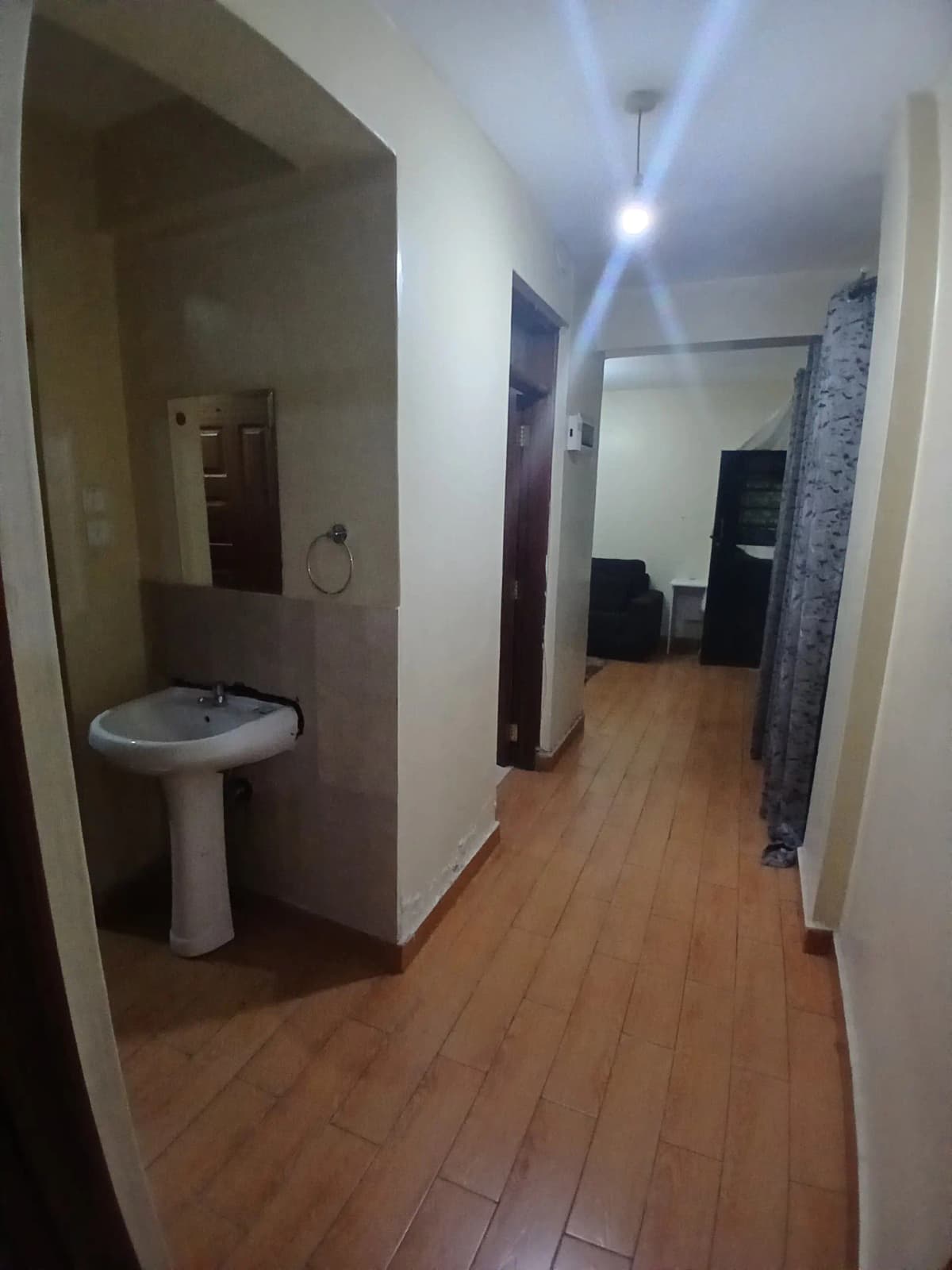 Hallway corridor with pedestal sink alcove and wooden flooring