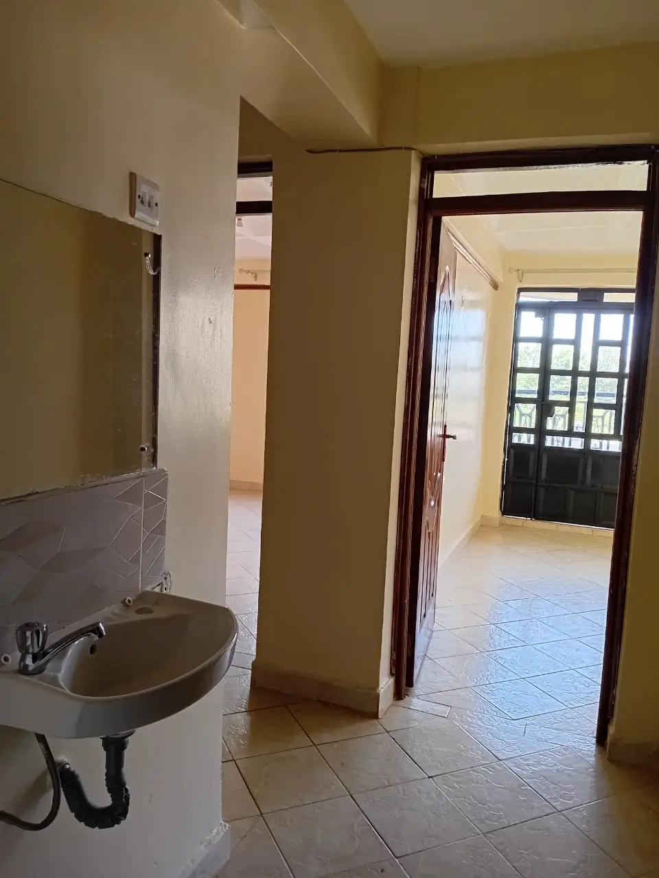Compact bathroom with wall-mounted sink and open corridor access