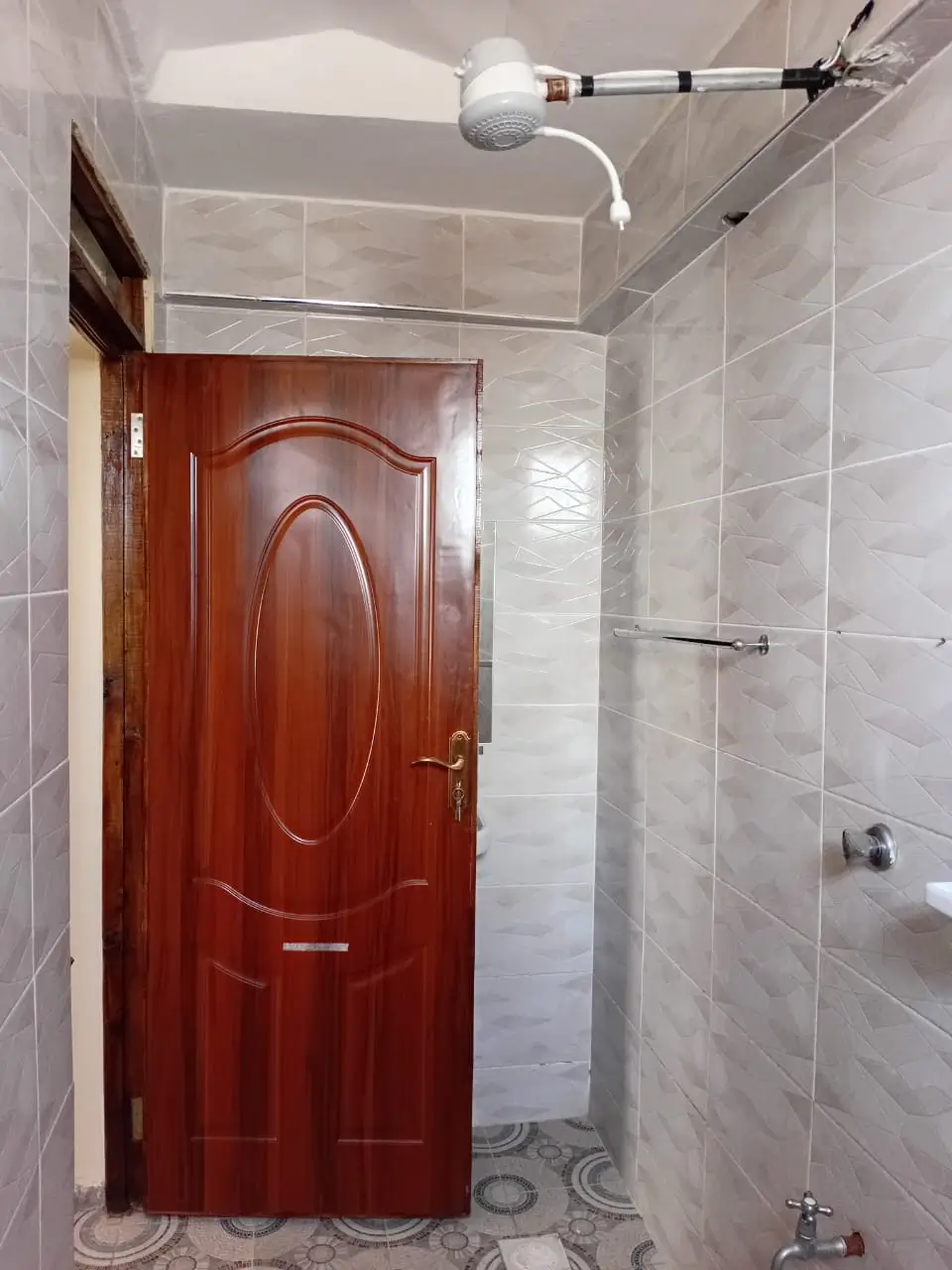 Bathroom with shower enclosure, red entry door, tiled walls