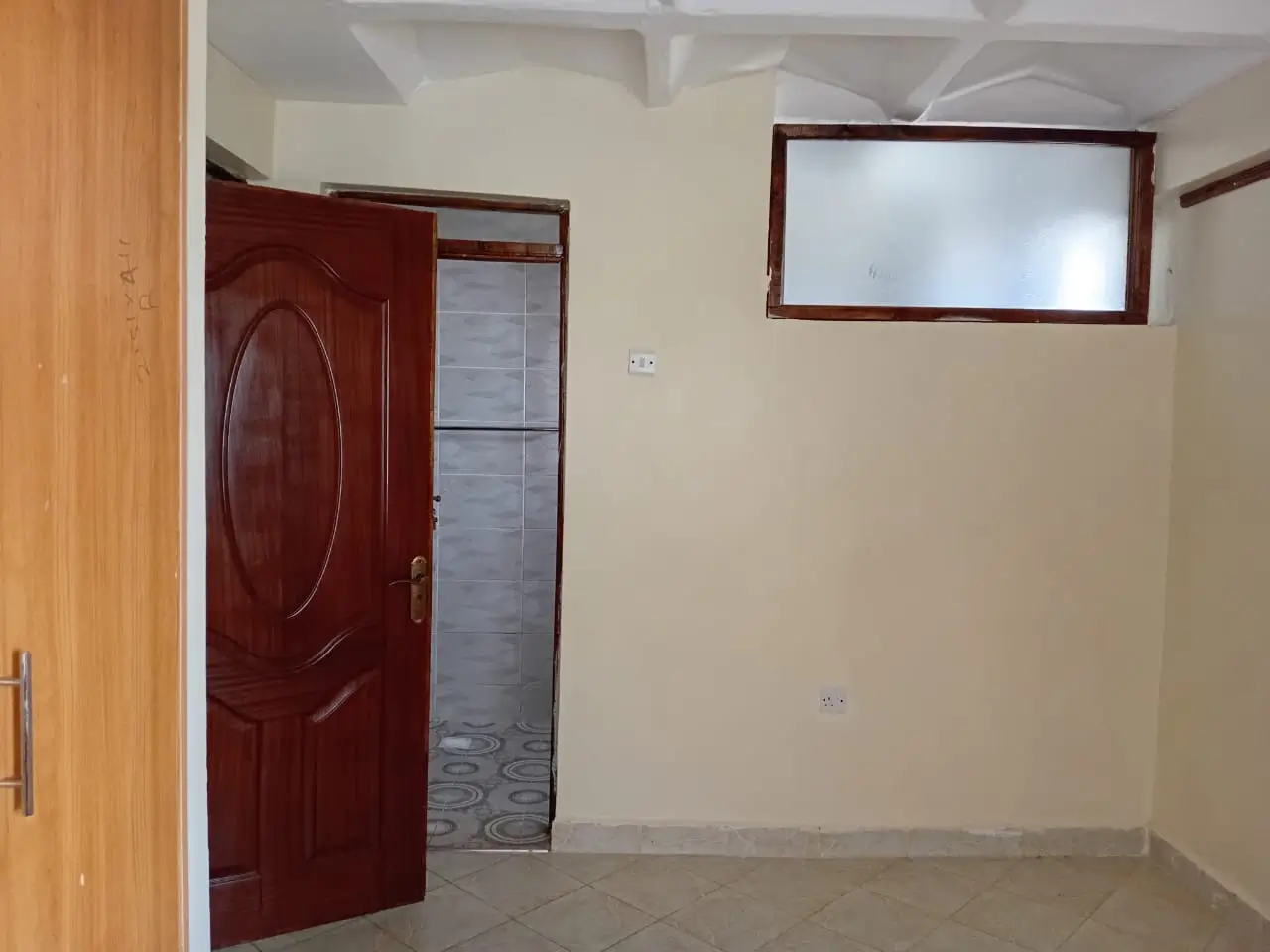 Unfurnished bedroom with red door and window