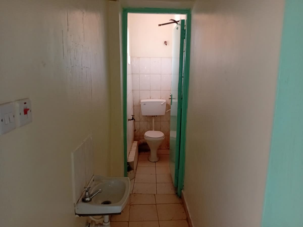 Compact bathroom with toilet, sink, and tiled walls