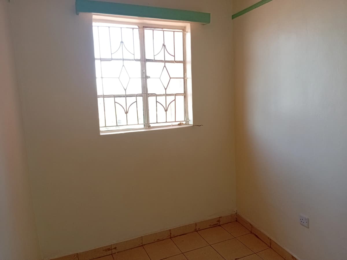 Simple bedroom with decorative window and terracotta tile floor