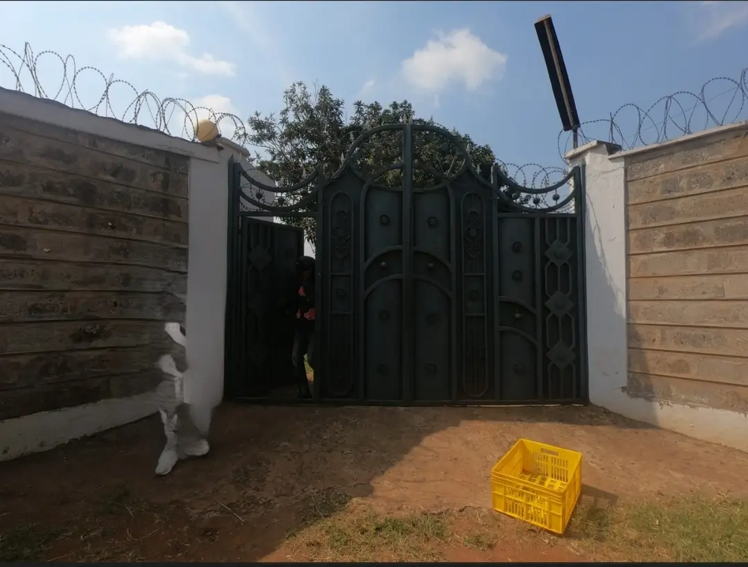 Secured driveway entrance with black metal gate and barbed wire