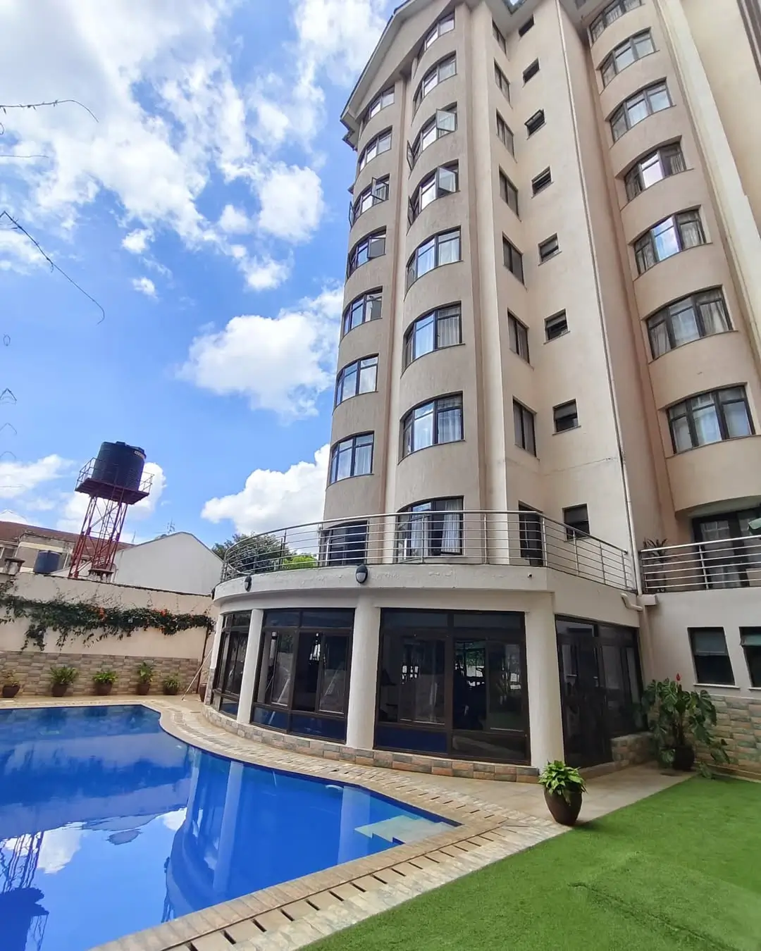 Resort-style swimming pool with manicured lawn and modern building