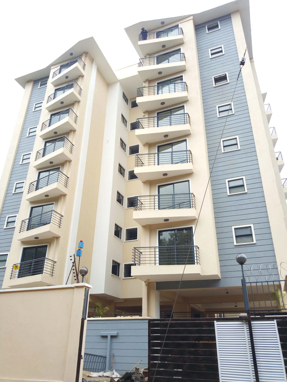 Modern multi-story residential building with balconies and secure gate