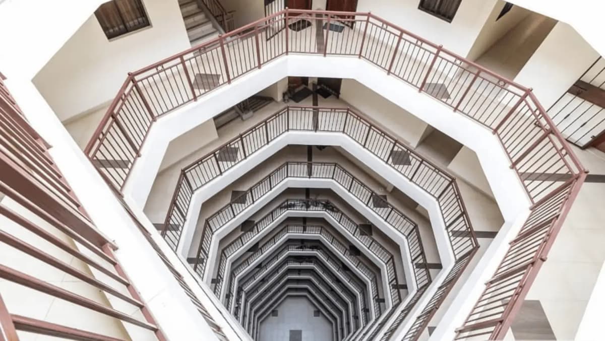 Multi-story spiral stairwell with metal railings, overhead view