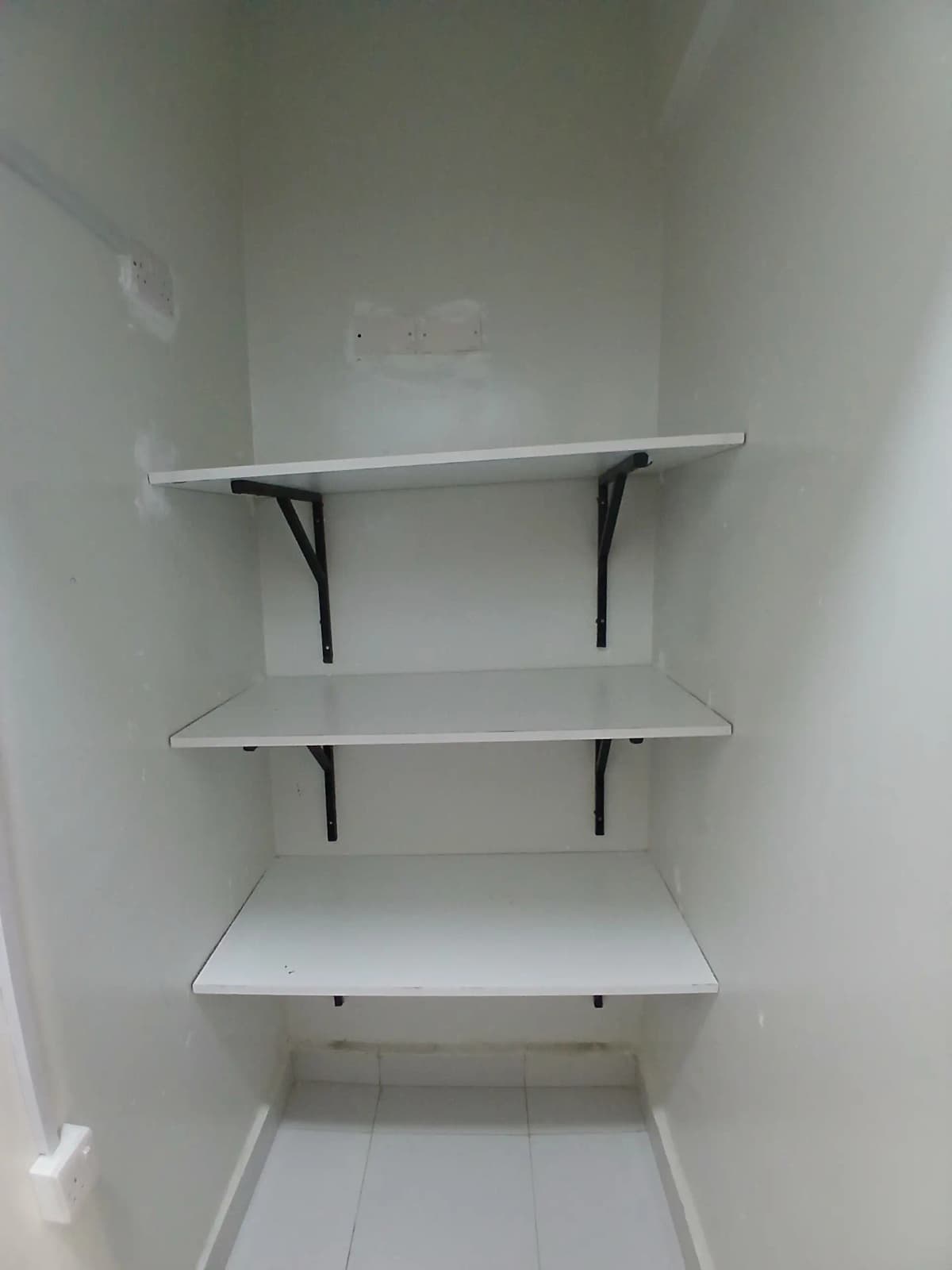 Empty shelving unit with three white shelves and black brackets