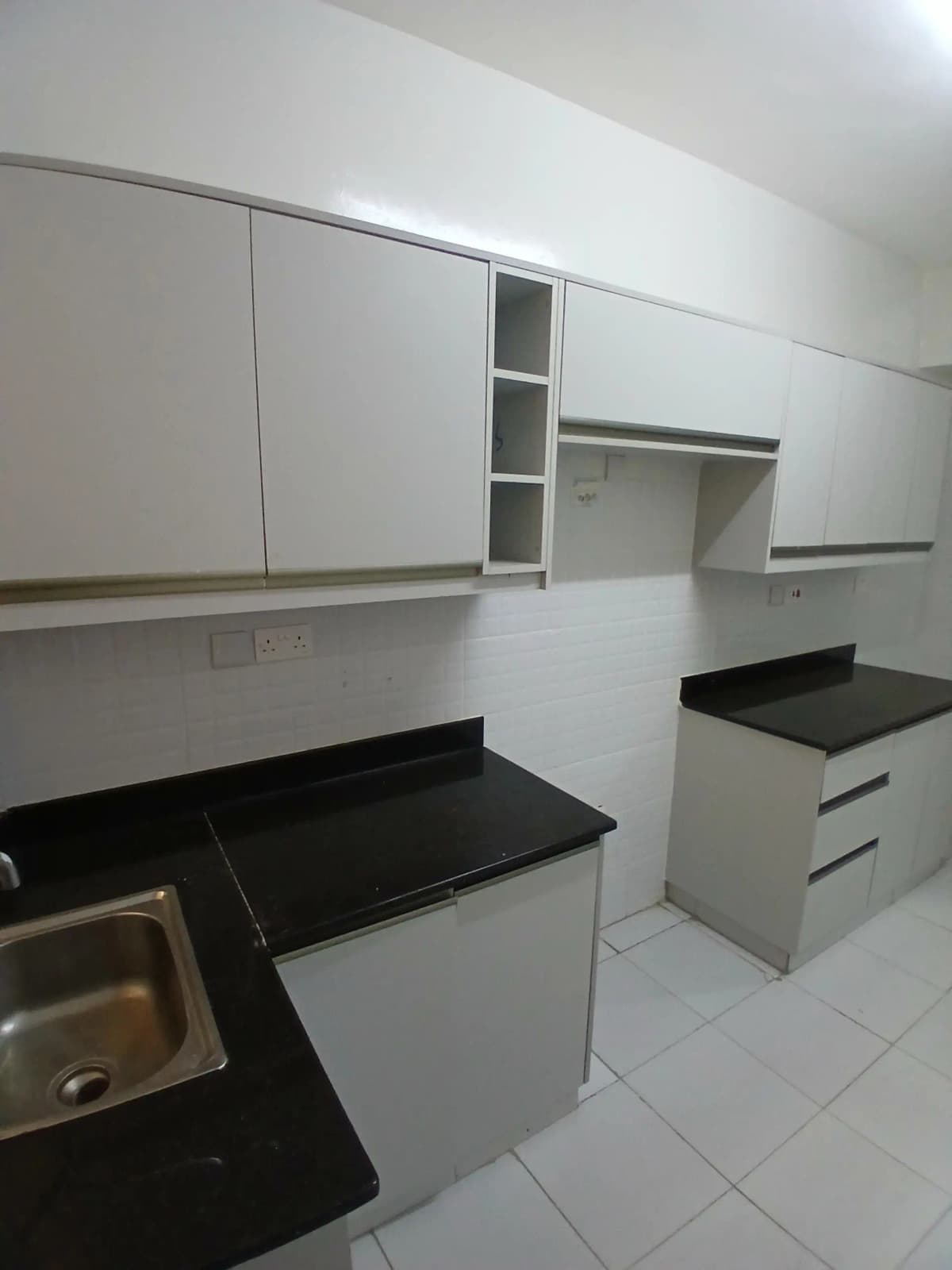 Modern kitchen with black countertops, white cabinetry, open shelving