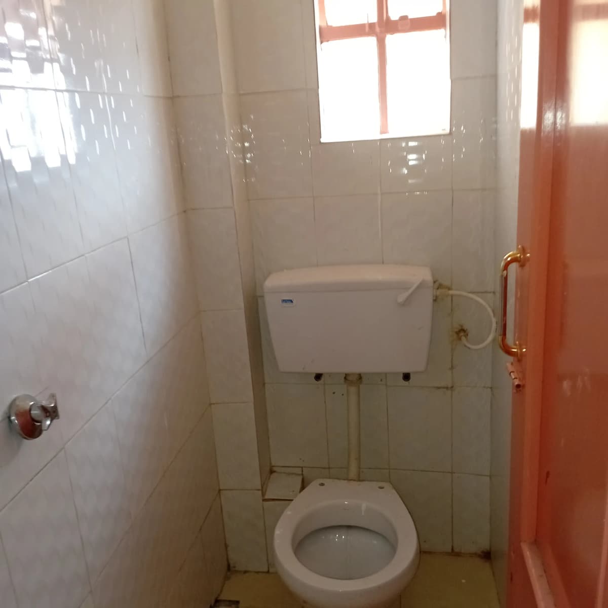 Compact bathroom with toilet, cistern, and window