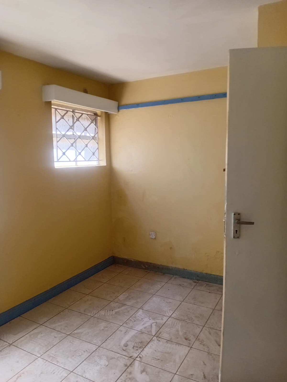 Compact bedroom with yellow walls and tile flooring