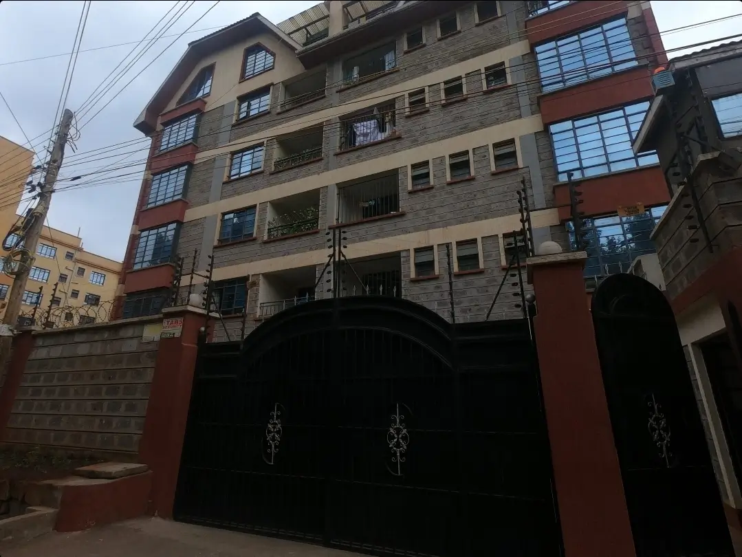 Multi-story residential building with red brick facade and gates