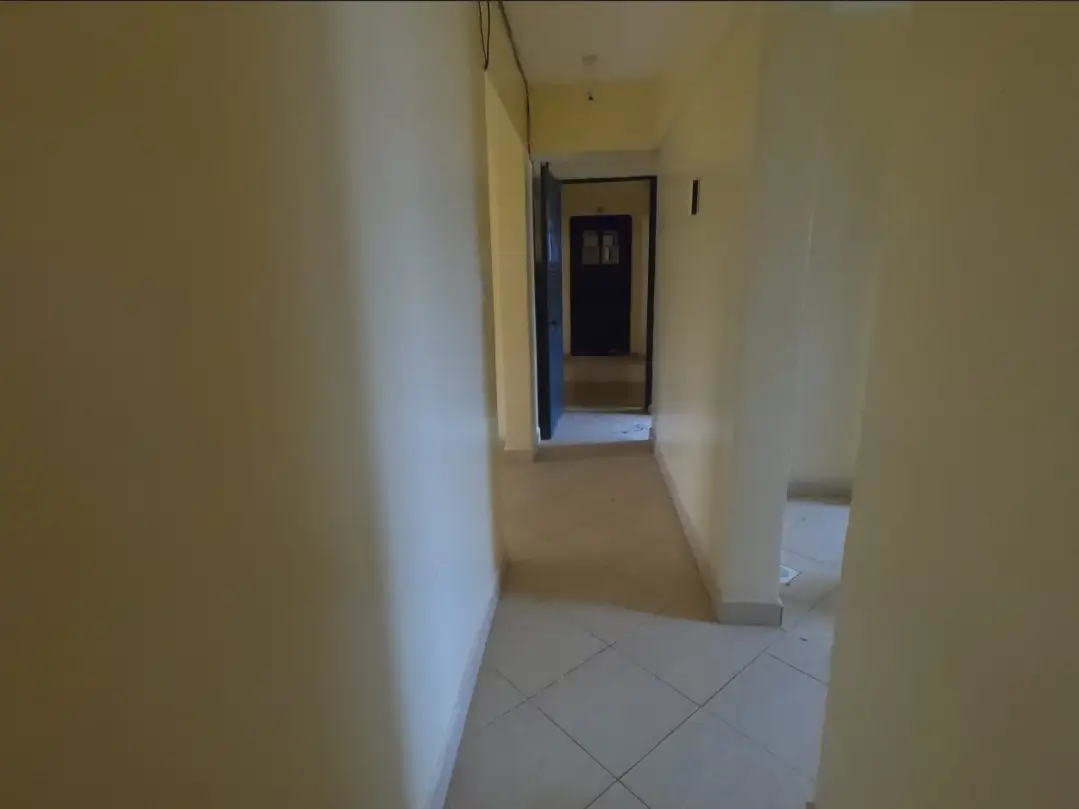 Long narrow corridor with tiled flooring and plain walls