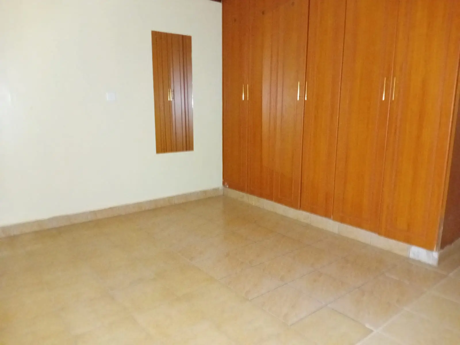 Spacious bedroom with wooden wardrobe and polished concrete floor