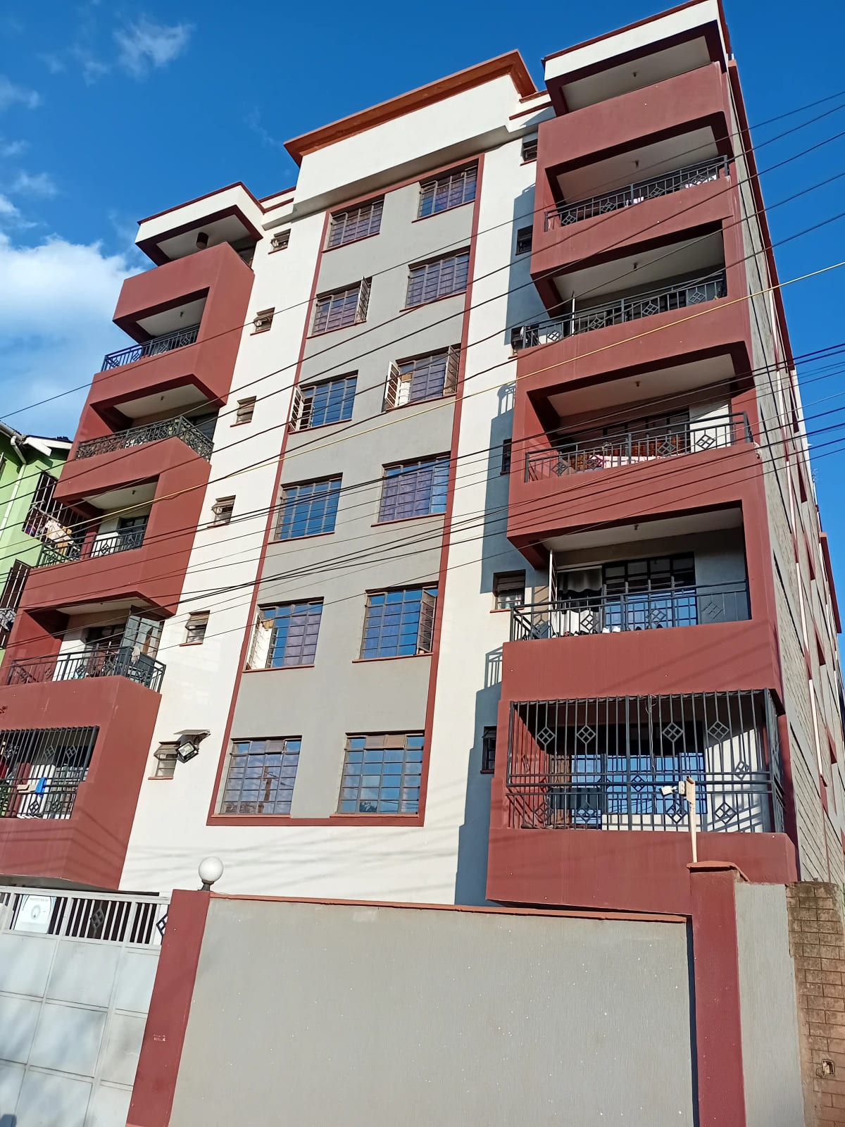 Multi-story residential building facade with red and cream exterior
