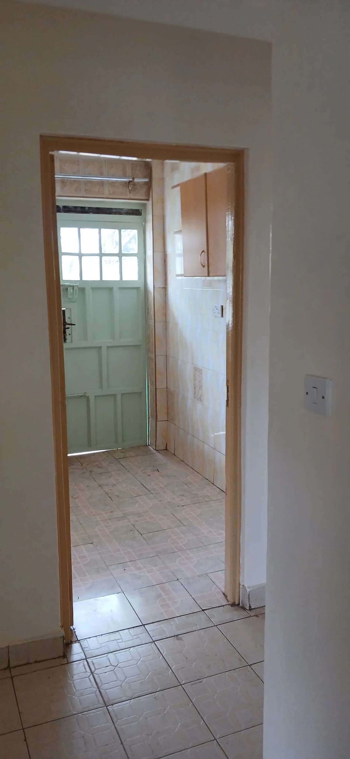 Bathroom with tiled floor and white sink visible through doorway
