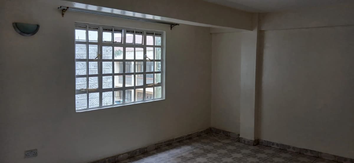 Empty bedroom with large barred window and tiled floor