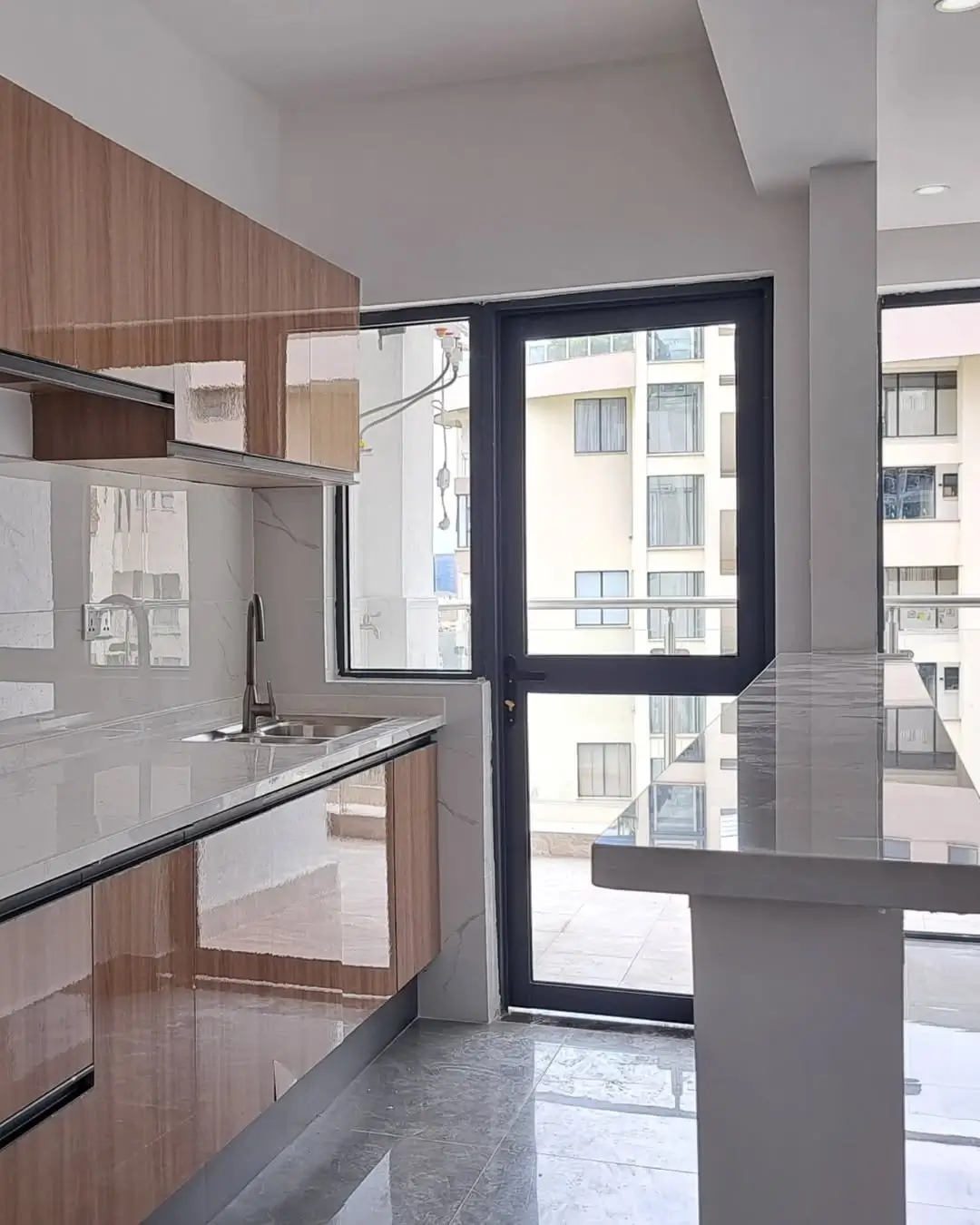 Modern kitchen with wood cabinetry and balcony access doors