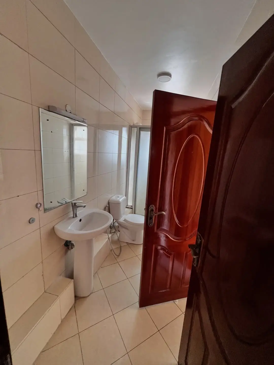 Bathroom with pedestal sink, toilet, mirror, and red door