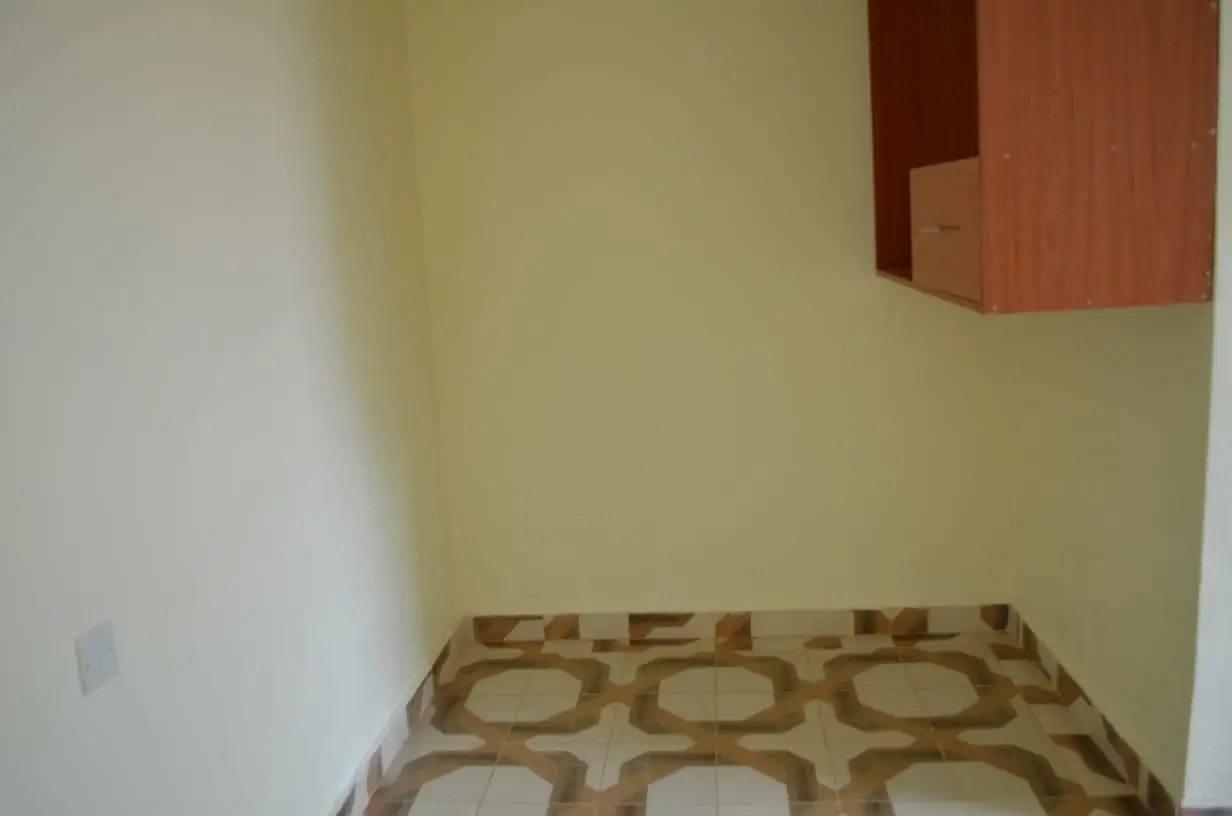 Small bedroom with patterned carpet and minimal furnishings
