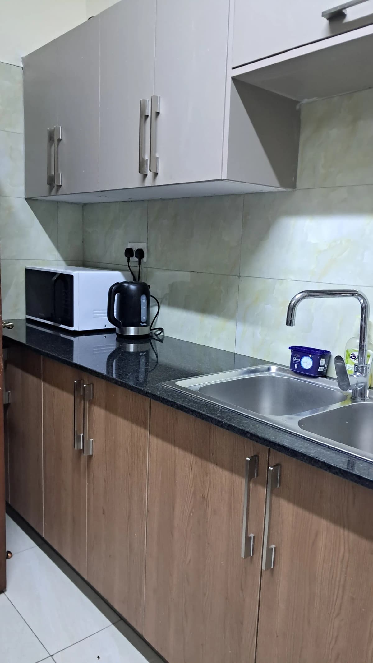 Modern kitchen with dark countertop, stainless steel sink, white upper cabinets