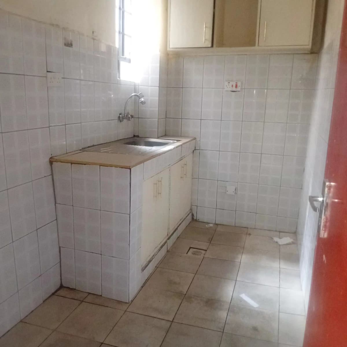 Compact kitchen with white tile walls and basic sink setup