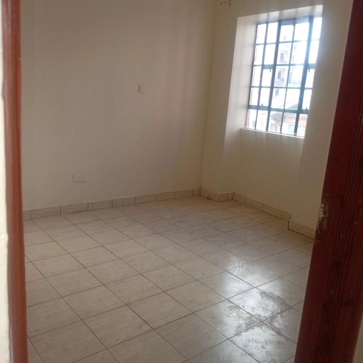 Spacious empty bedroom with tiled floor and natural light