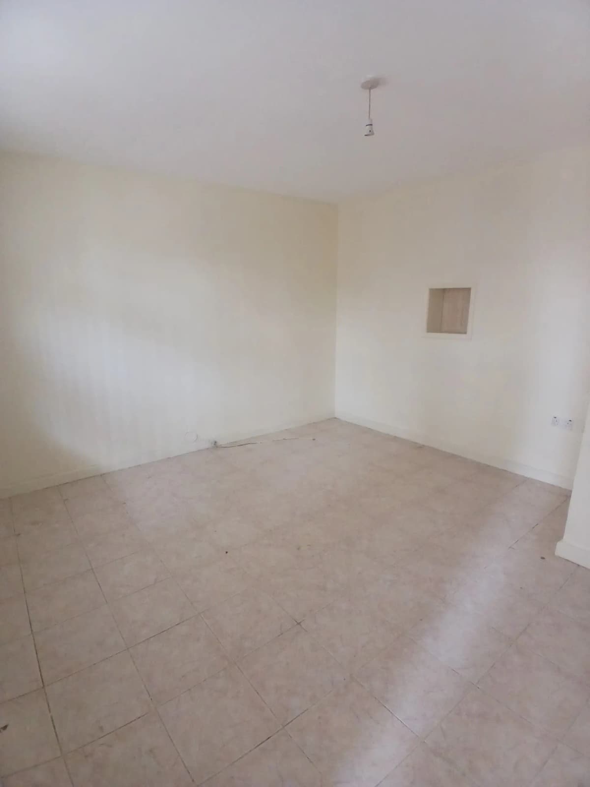 Empty bedroom with tiled floor and small window opening