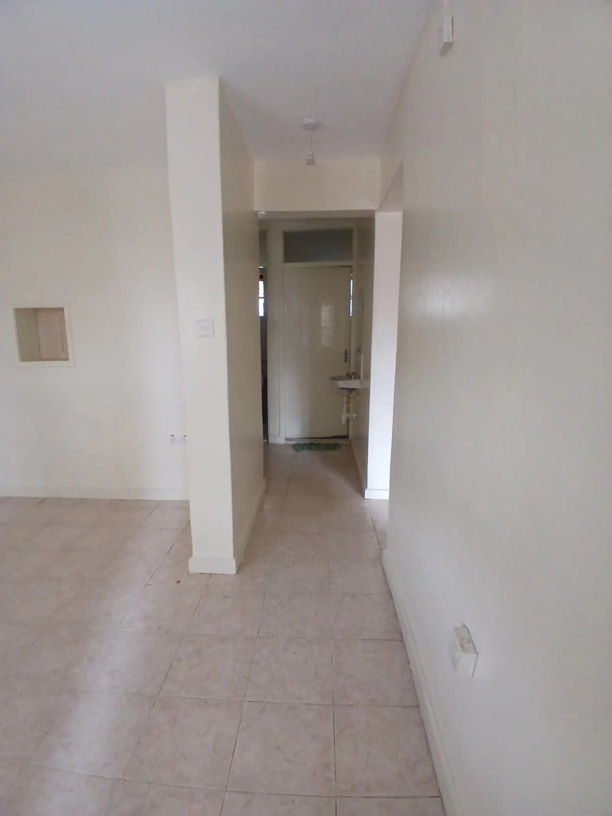 Narrow hallway with white walls and tiled flooring