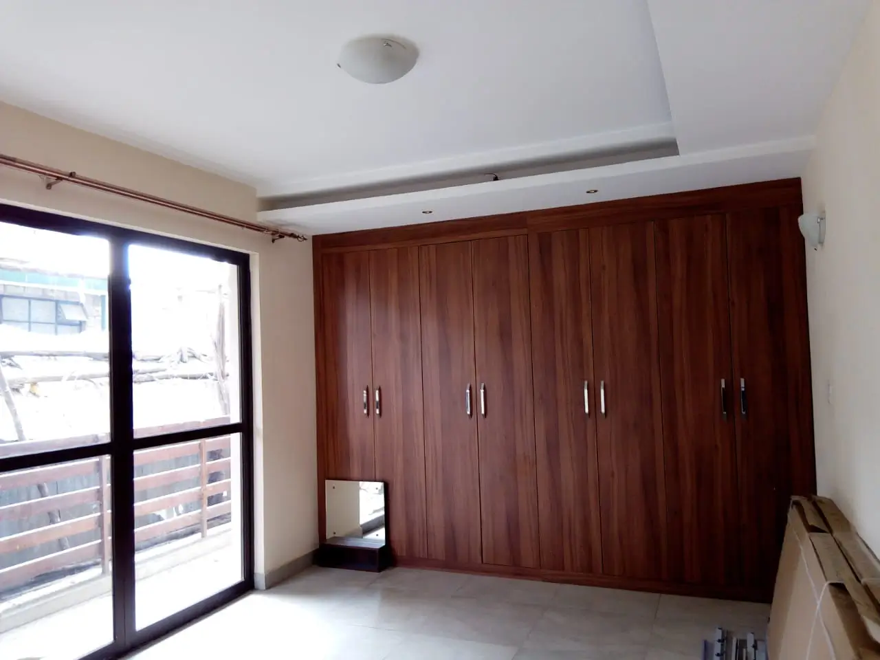 Spacious bedroom with built-in wooden wardrobe and balcony access