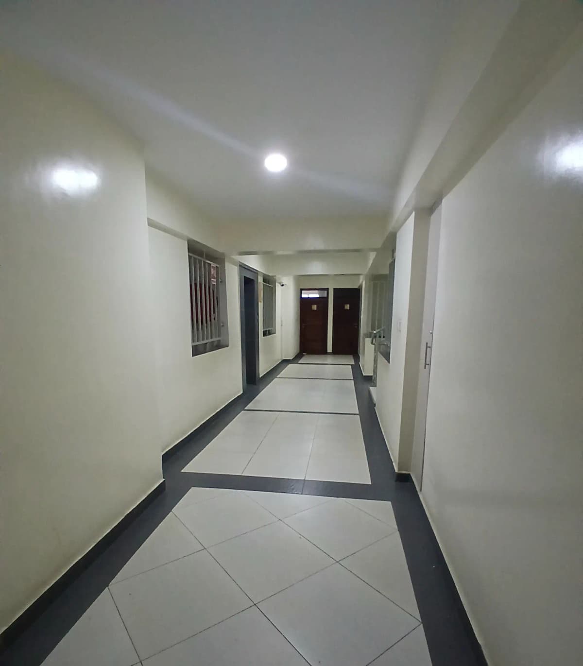 Bright corridor with two-tone tile flooring and recessed lighting