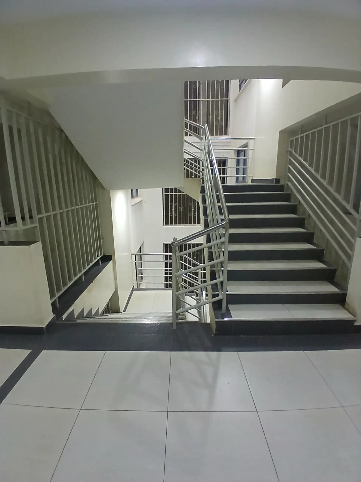 Multi-level staircase with metal railings and tiled flooring