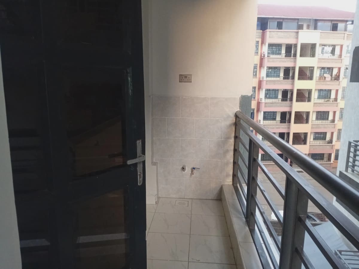 Compact balcony with metal railing overlooking residential buildings